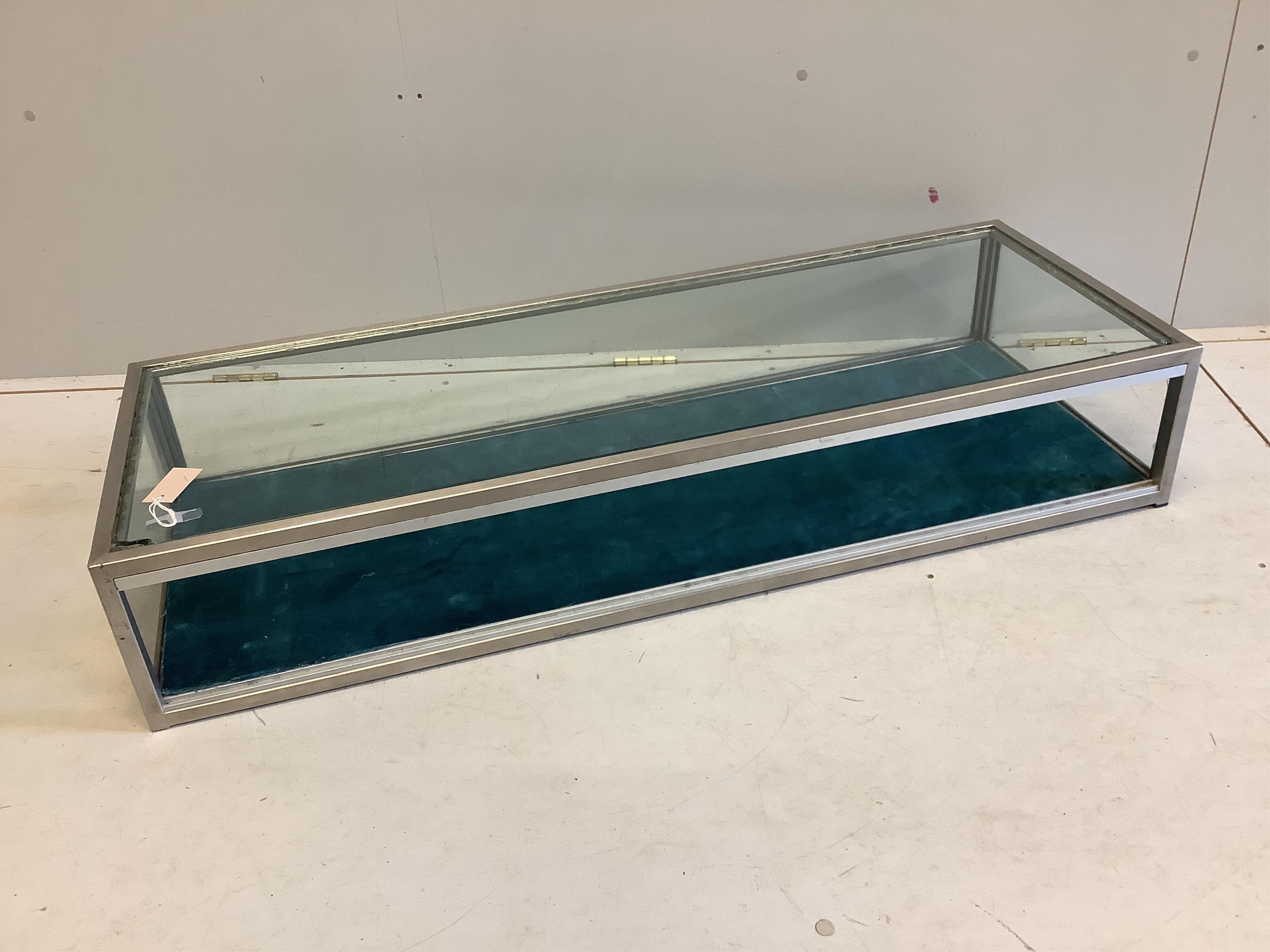 A modern brushed steel and glass counter top jewellery display case, width 128cm, depth 47cm, height 23cm. Condition - poor, glass top damaged to one corner, lacks sliding doors.